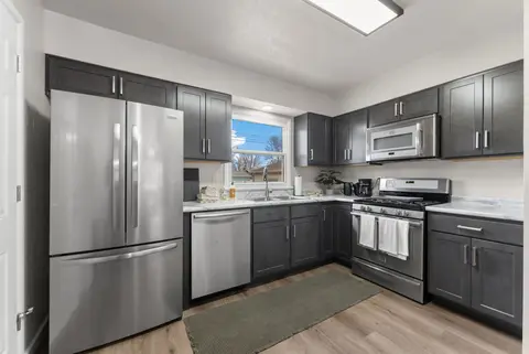 Kitchen with dark cabinets, a French-door refrigerator, a dishwasher, and a gas range