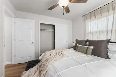 Queen bed with a knit throw beside a closet and the bedroom door