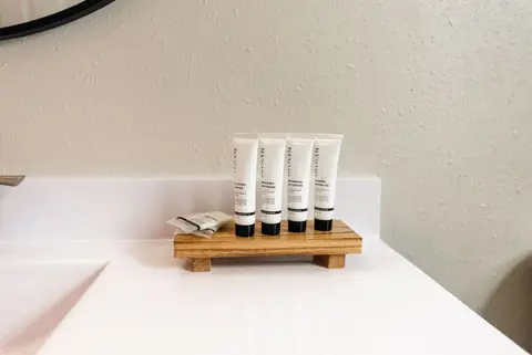 Travel-size toiletries on a wood tray on the bathroom counter