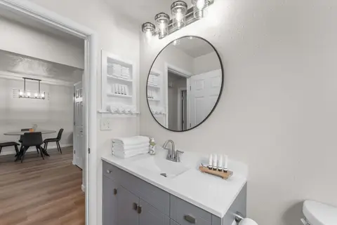 Bathroom vanity with a round mirror, looking out to the dining area
