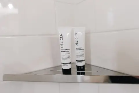 Two tubes of shower products on a corner shelf