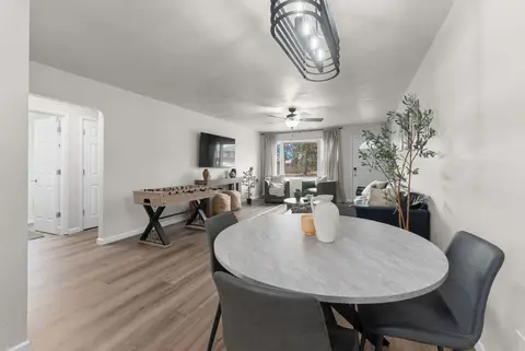 Round dining table with gray chairs, looking into the living room