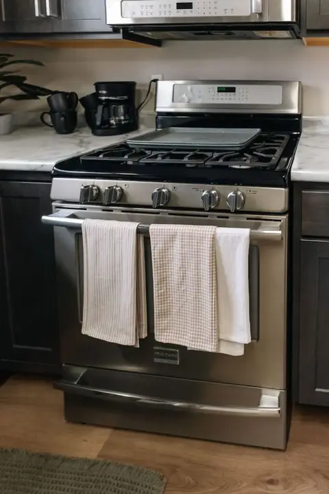 Dish towels hanging on the oven door of the gas range