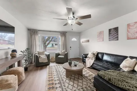 Living room with a leather sectional, fern prints on the wall, and a ceiling fan