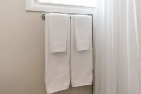 White towels on a bar beside the shower curtain