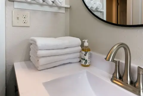 Folded white towels and hand soap beside the bathroom sink