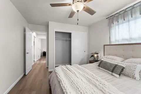Queen bed beside an open closet and the bedroom door