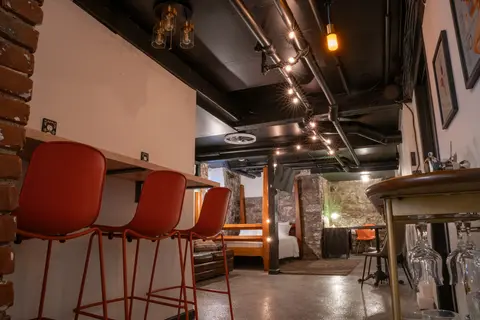 Red bar stools at the counter, with the studio and stone walls beyond