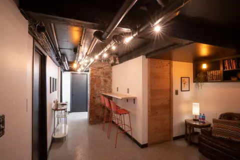 Hall past the bar counter and the cedar sauna door, with a lamp and armchair