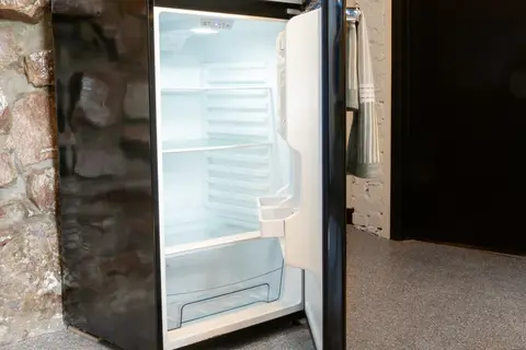 Open refrigerator beside the stone wall