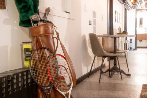 Vintage golf bag and tennis rackets beside a café table and chairs