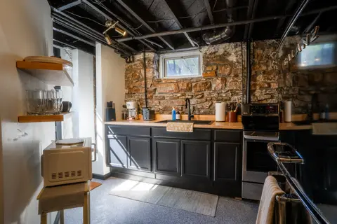 Kitchen with black cabinets, butcher block counters, and an electric range below a basement window