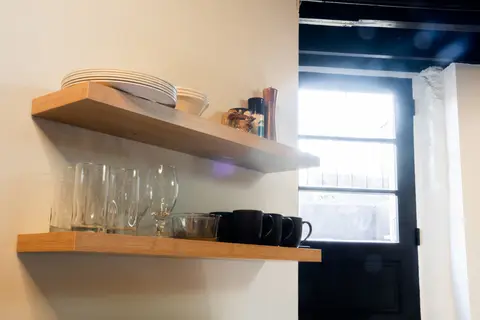 Open shelves with plates, glasses, and mugs beside the entry door