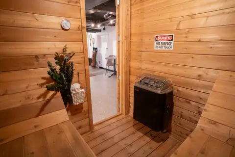 Cedar-lined sauna with a heater, a plant, and a towel basket by the door