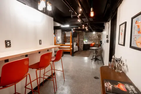 Wall counter with red bar stools, looking toward the bed at the far end of the studio