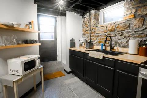 Kitchen with open shelves, a microwave, and the door to the entry steps