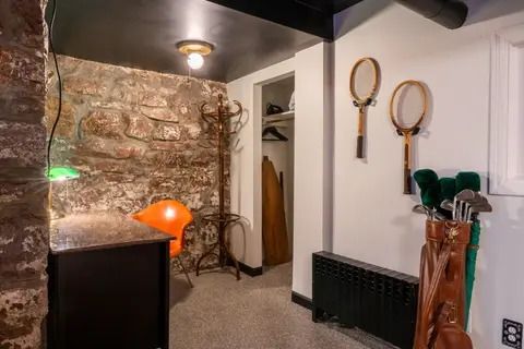 Desk nook with an orange chair, vintage rackets on the wall, and a golf bag