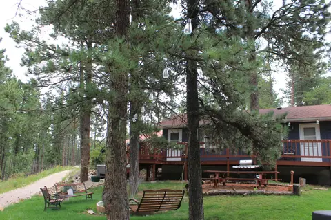 Lawn with benches and a swing among the pines beside the main building