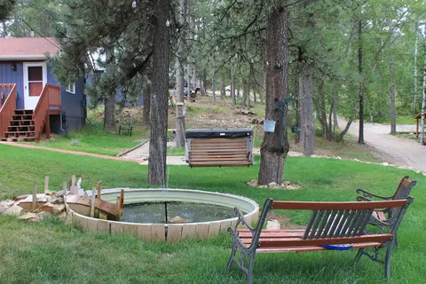 Pond with a bench on the lawn, with the cabins beyond