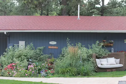 Flower beds and a wicker daybed along the blue building