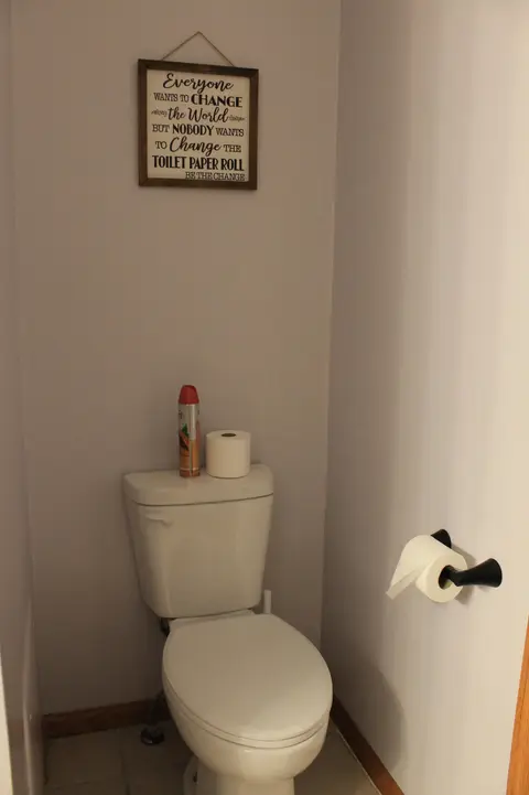 Toilet with a framed sign above it