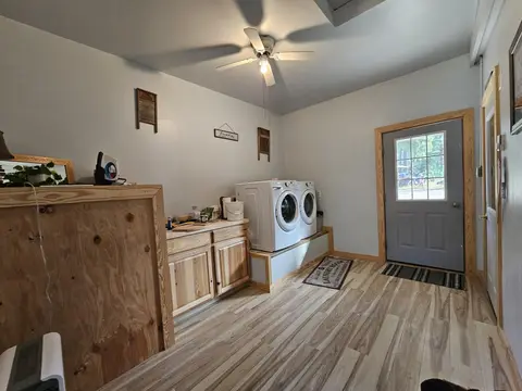 Shared laundry room with a front-load washer and dryer and wood cabinets
