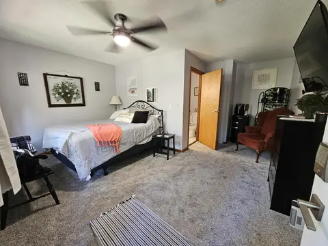 Studio with a queen bed, a bench, a wingback chair, and a wall-mounted TV