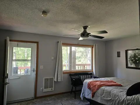 Queen bed by the window, with a ceiling fan and a glass-paned door