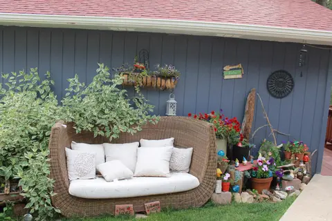 Wicker daybed with white cushions among the flowers