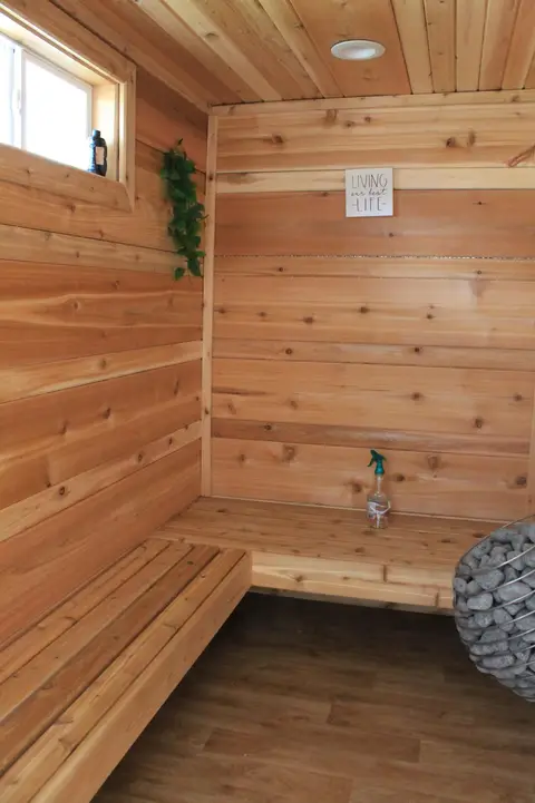 Wood-lined sauna with benches and a heater full of stones