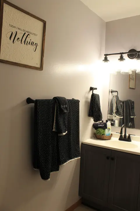 Bathroom vanity with dark towels and a framed sign