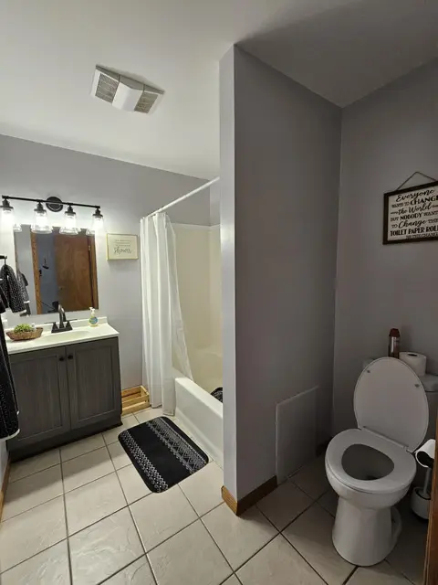 Bathroom with a vanity, a tub and shower behind a curtain, and a toilet