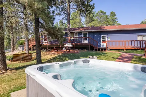 Shared hot tub on the lawn, with the main building and a porch swing behind
