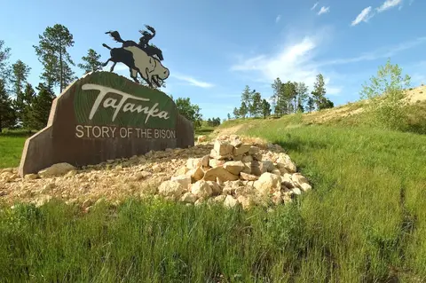 Tatanka: Story of the Bison sign with a rider sculpture