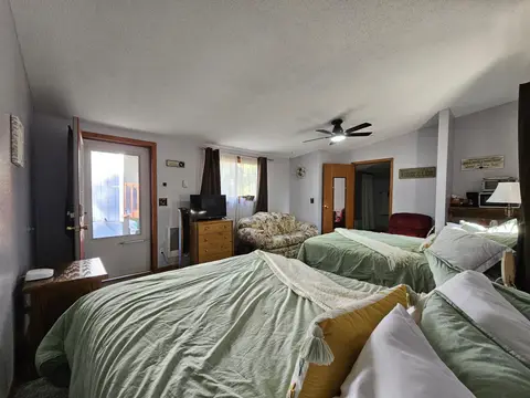 Two queen beds with green bedding, a dresser, and a glass-paned door