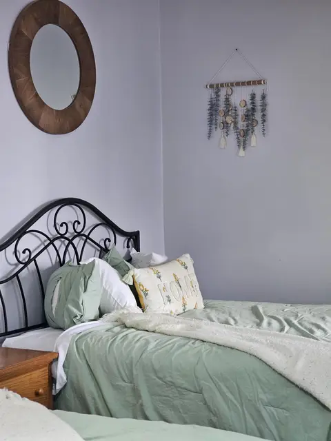 Queen bed with an iron headboard under a round mirror