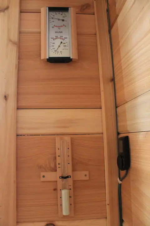 Sauna thermometer and sand timer on the wood wall
