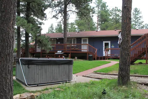 Covered hot tub on the lawn, with the main building’s deck behind
