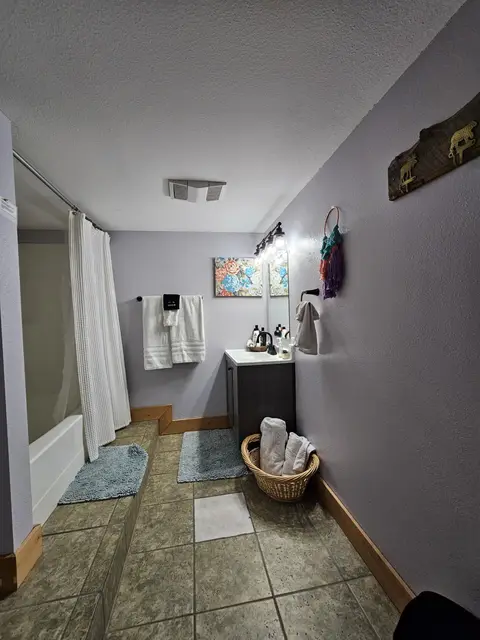 Bathroom vanity, a towel basket, and a tub with a white shower curtain
