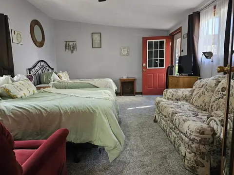 Two queen beds, a floral sofa, and a red door with a window