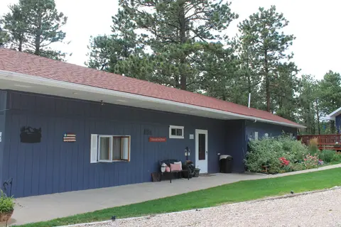 Blue main building with a bench by the door and a gravel drive