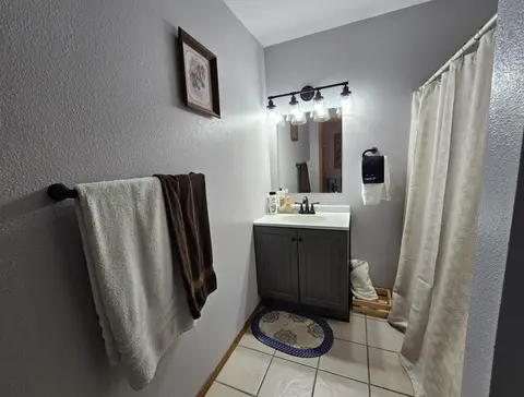 Bathroom with a vanity, a tub and shower behind a curtain, and towels