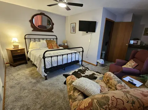 Studio with an iron queen bed, a wall-mounted TV, and a floral sofa
