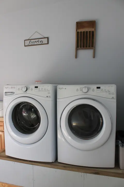 Front-load washer and dryer under a laundry sign and a vintage washboard