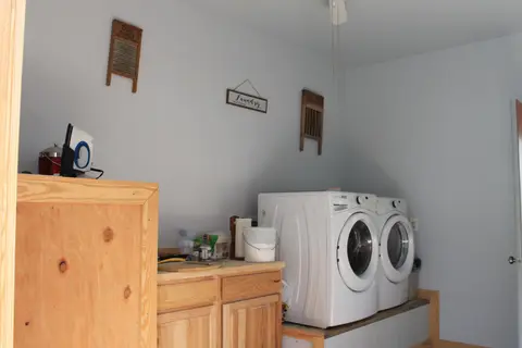 Front-load washer and dryer on a platform beside wood cabinets