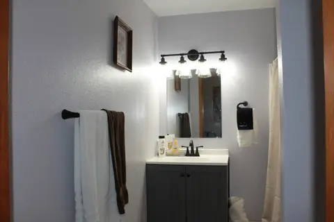 Bathroom vanity with a lighted mirror and dark towels