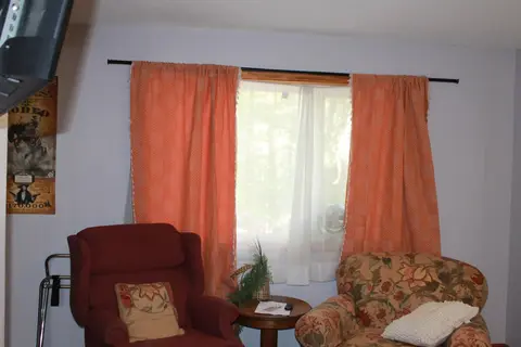 Two armchairs and a small round table by a curtained window