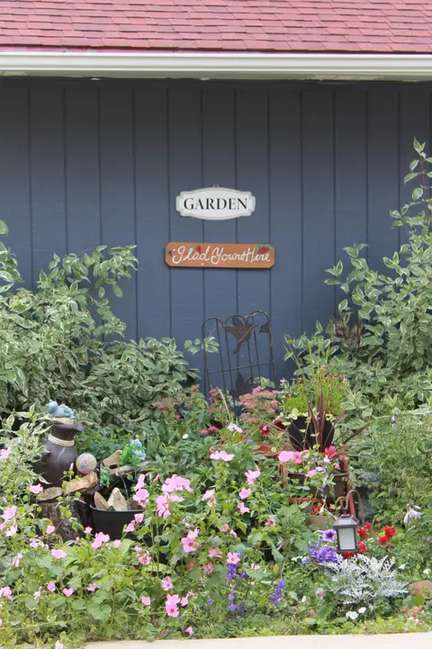 Flower garden under Garden and Glad You’re Here signs