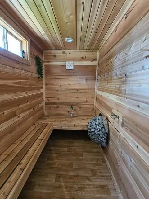Long wood-lined sauna with benches, a window, and a stone heater