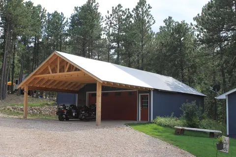 Carport and garage among the pines at the end of a gravel drive